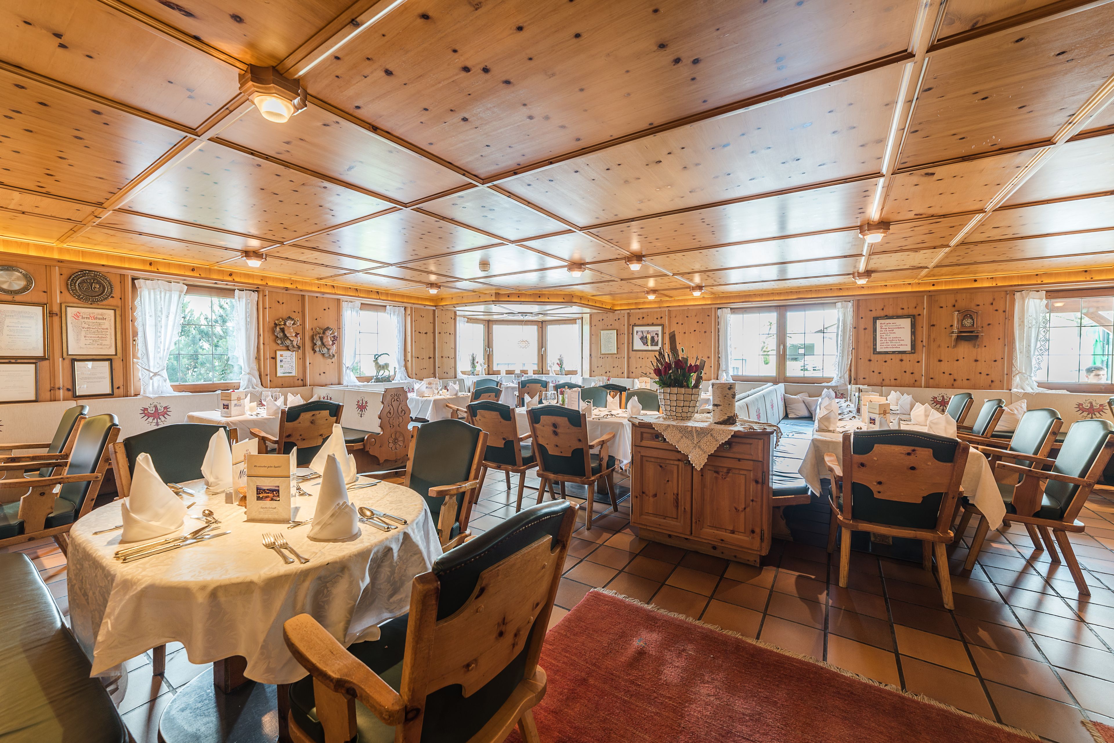 A restaurant with wooden interiors, multiple tables, and chairs.