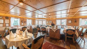 A restaurant with wooden interiors, multiple tables, and chairs.