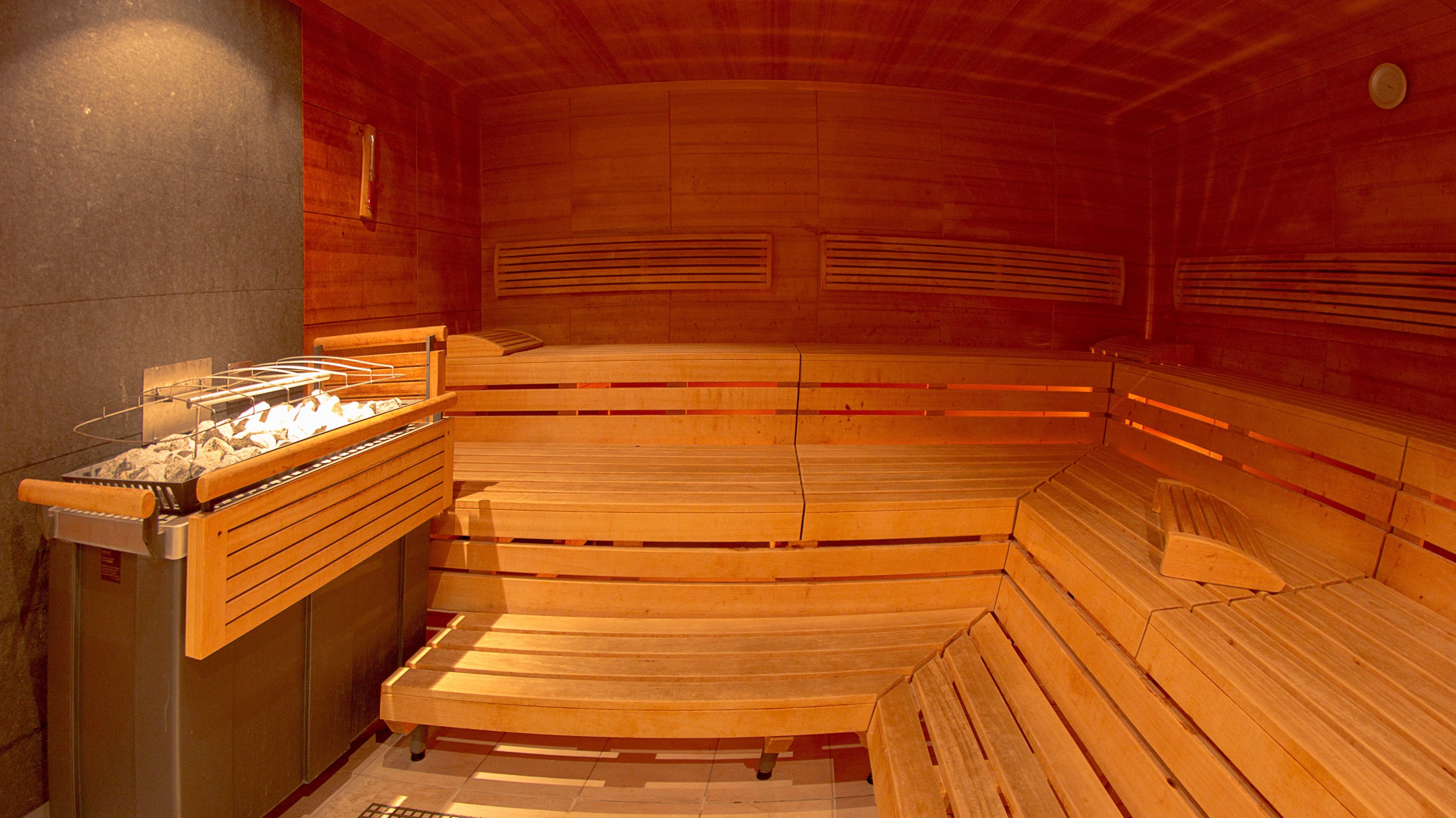 A sauna with wooden benches and a stone wall.