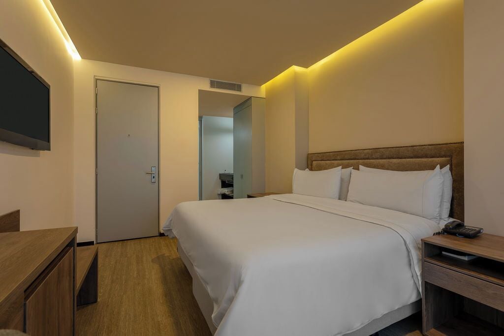Habitación de hotel con cama, mesita de noche y escritorio.
