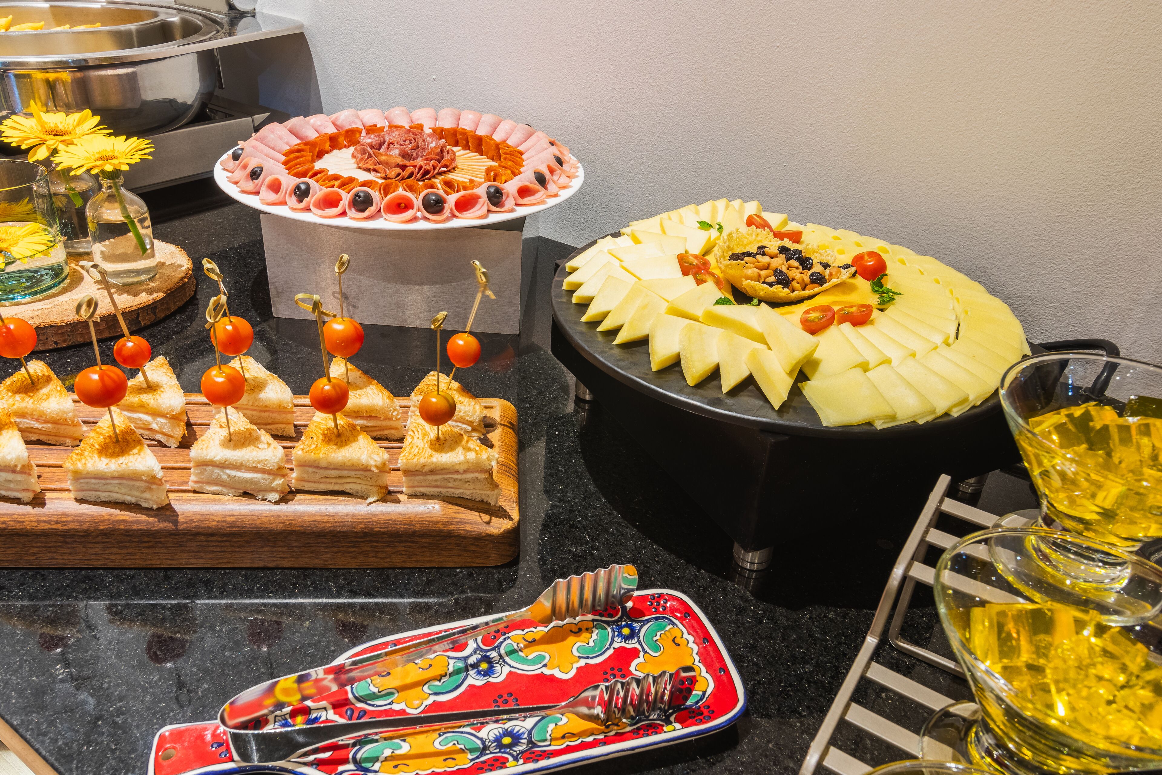 A buffet table with various food items, including cheese, meats, and fruit.