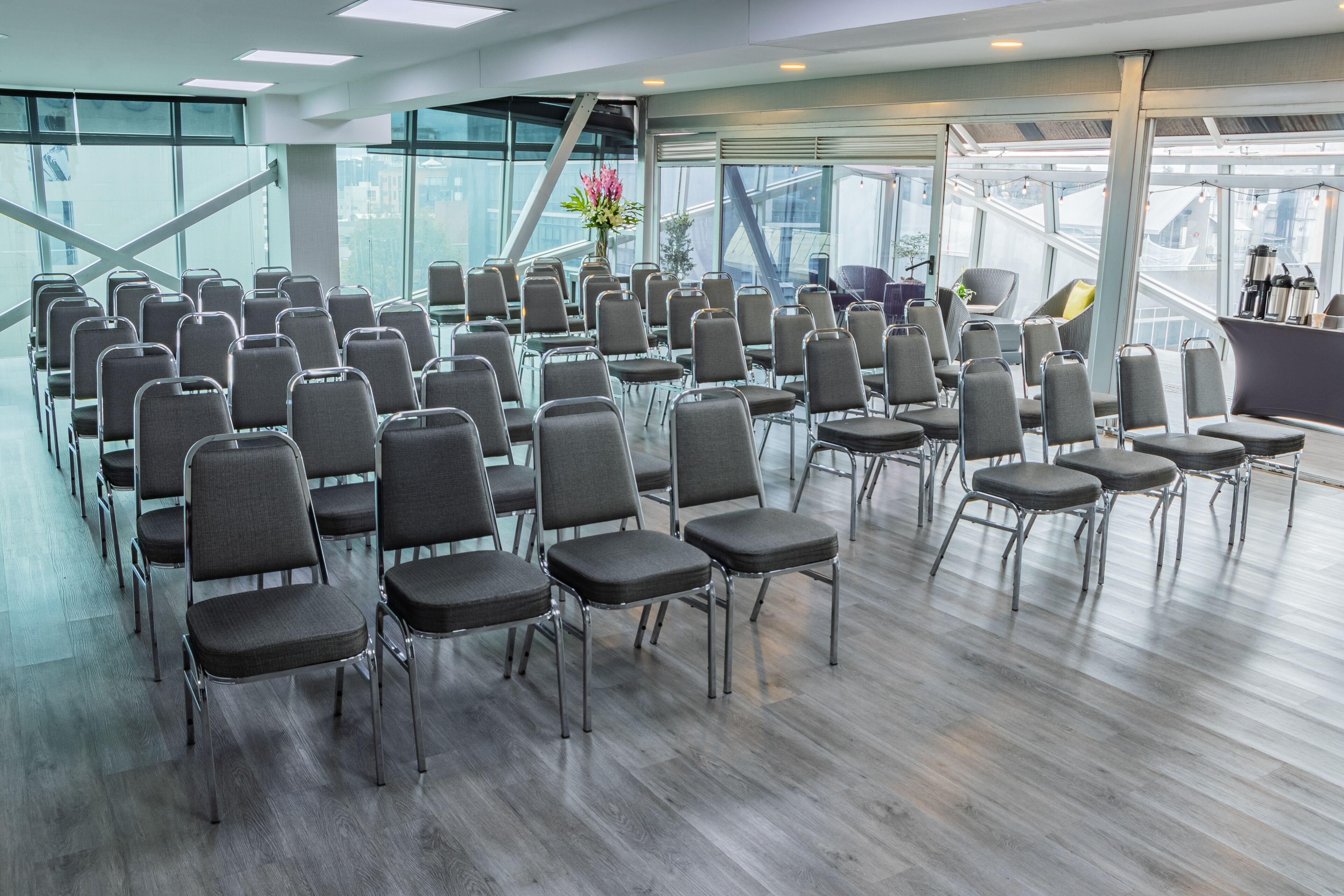 A conference room with rows of chairs, a large window, and a staircase.