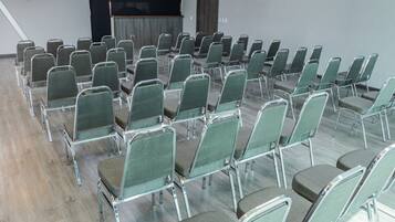 Un salón de conferencias con filas de sillas verdes y suelo de madera.