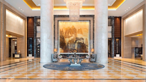 A lobby with a large mural, a chandelier, and a checkered floor.