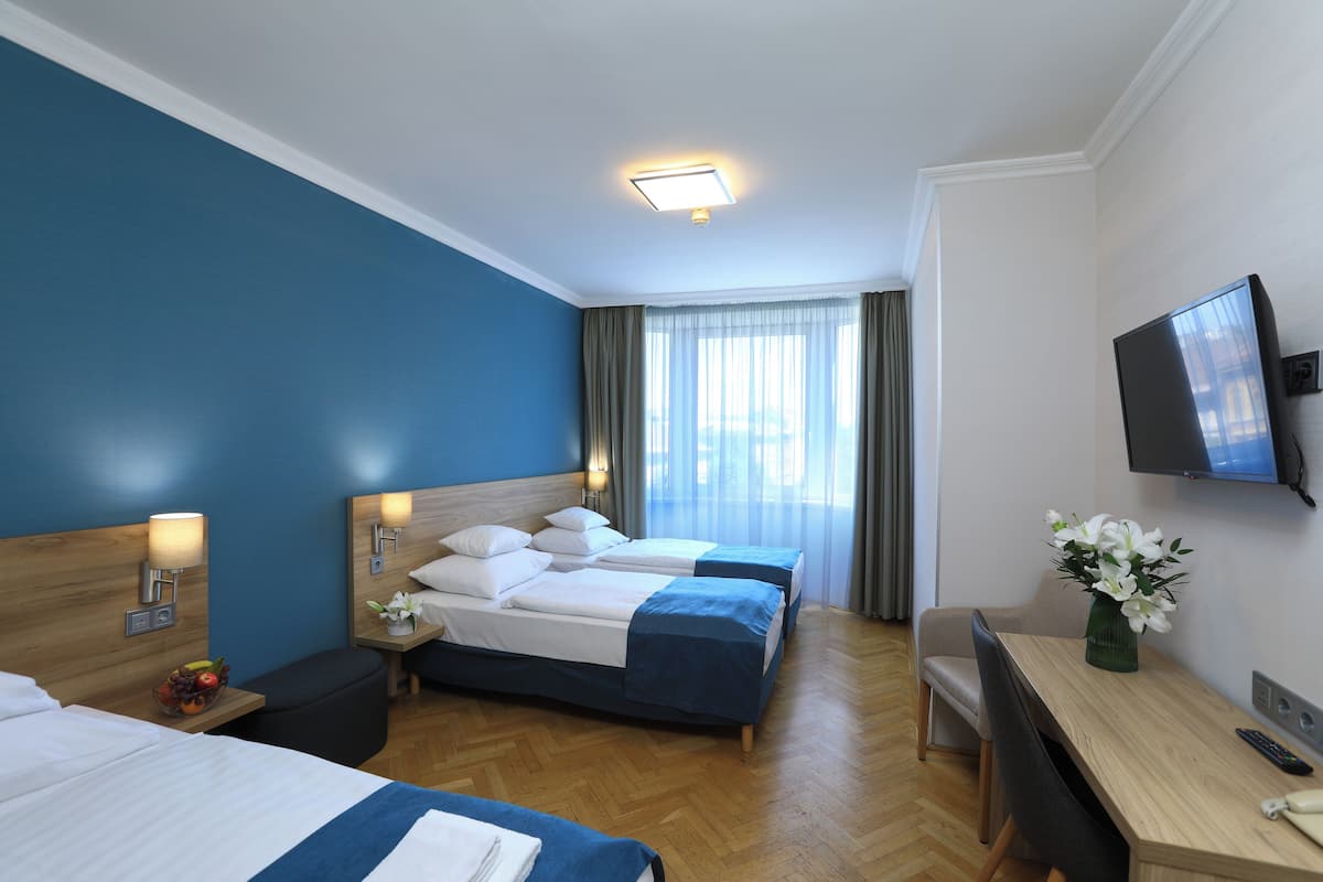 Une chambre d’hôtel avec deux lits, un bureau, une télévision et une fenêtre avec des rideaux.