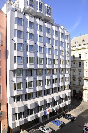 Un hotel moderno a più piani, con diverse balconate e un'area di parcheggio con diverse auto.