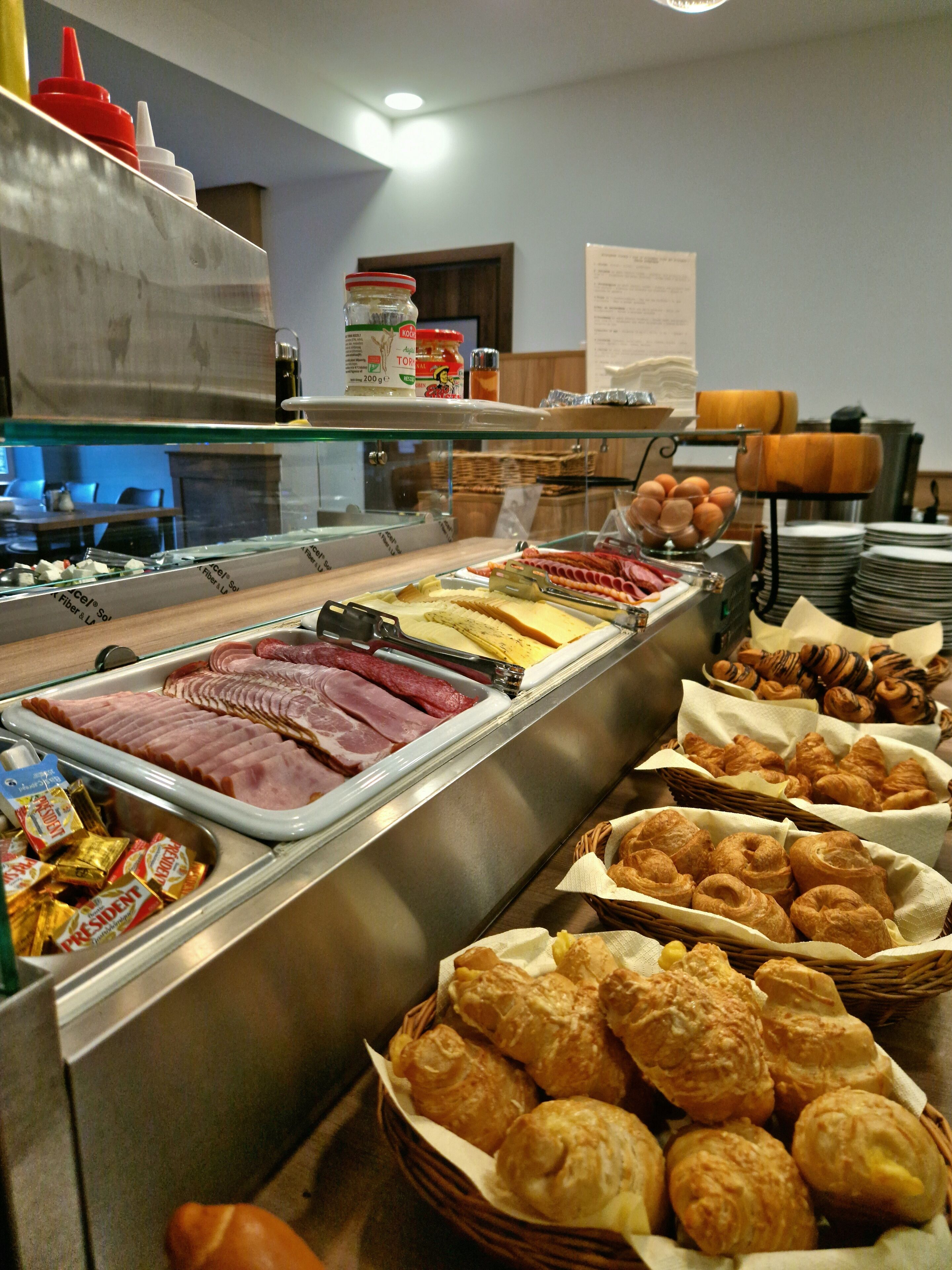 A buffet with various food items including meats, cheeses, and pastries.