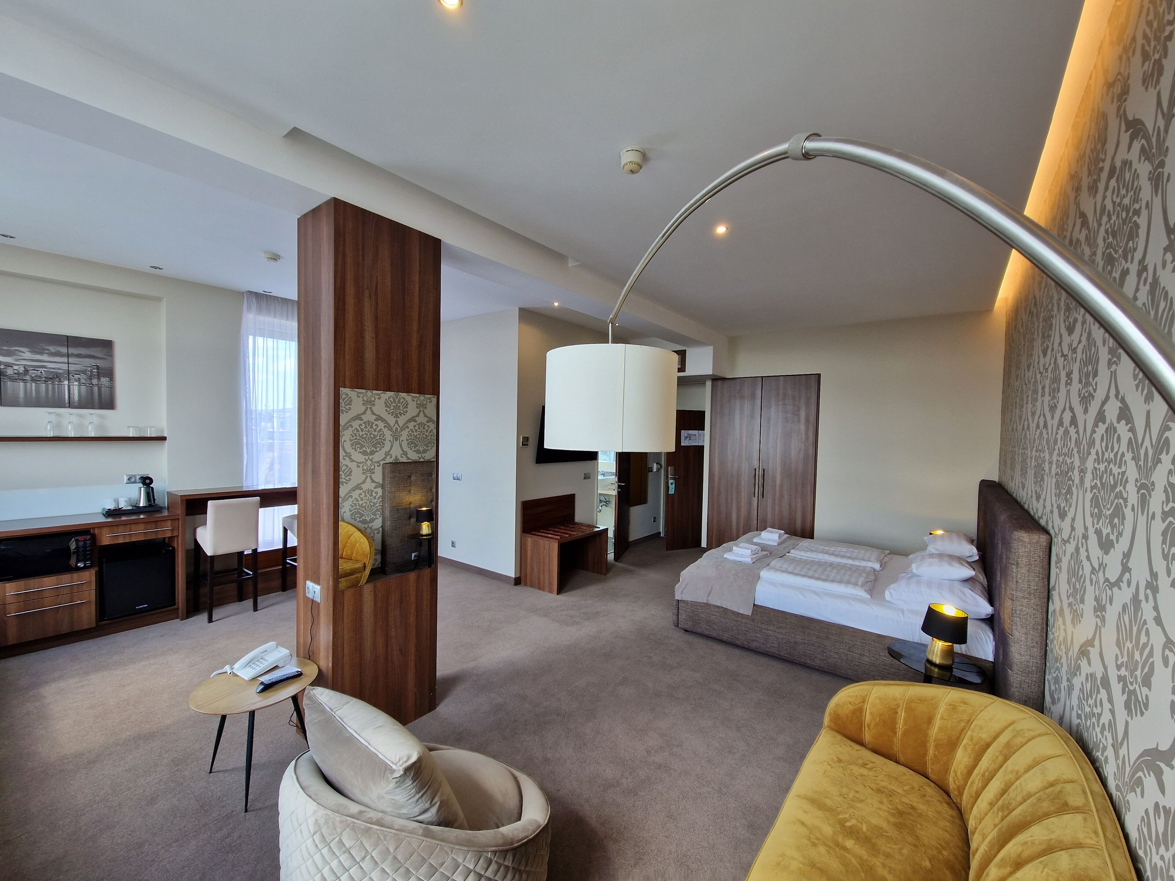 Een hotelkamer met een bed, een bureau, een stoel, een bank en een lamp.