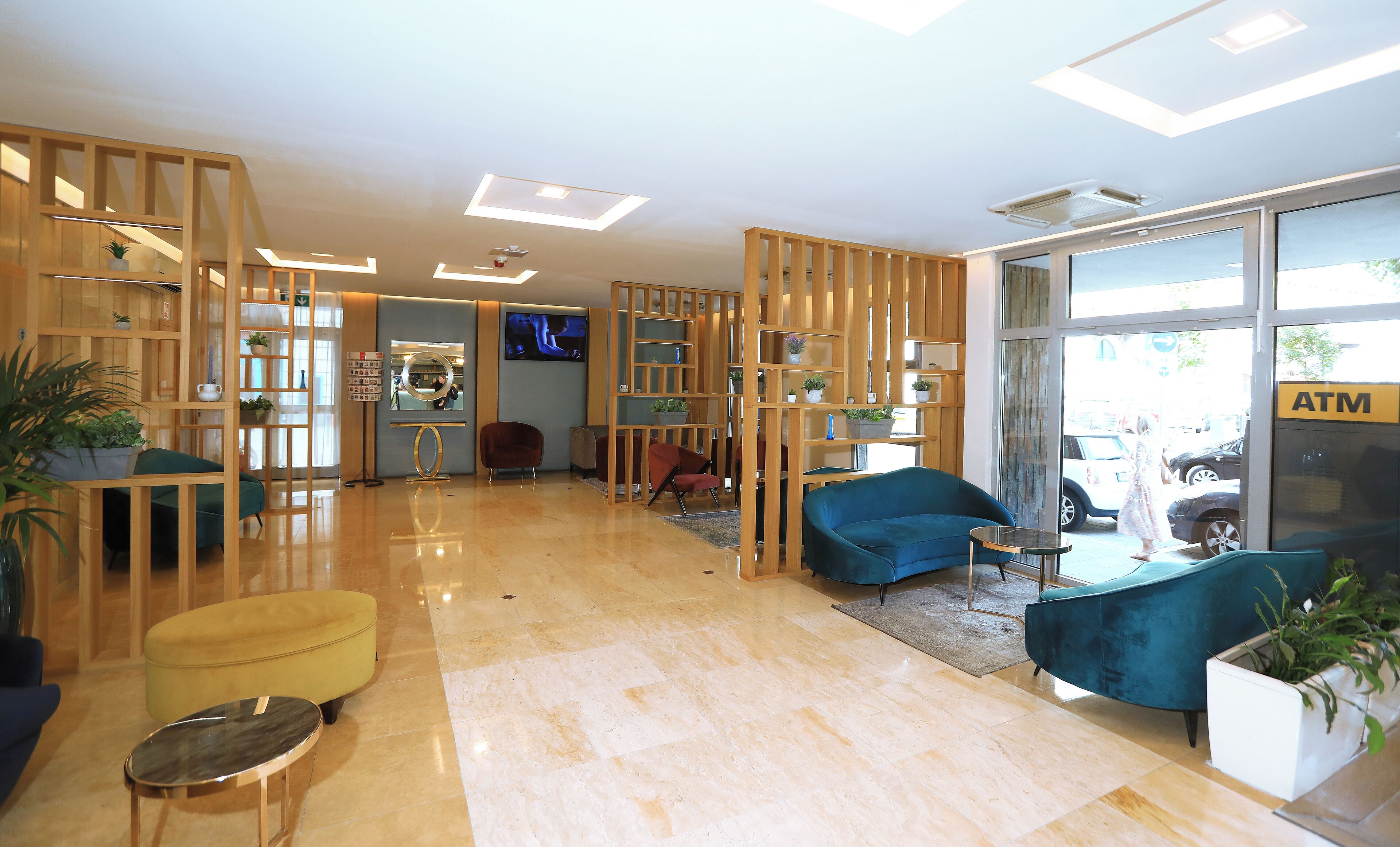 A modern lobby with wooden partitions, comfortable seating, and a visible ATM.