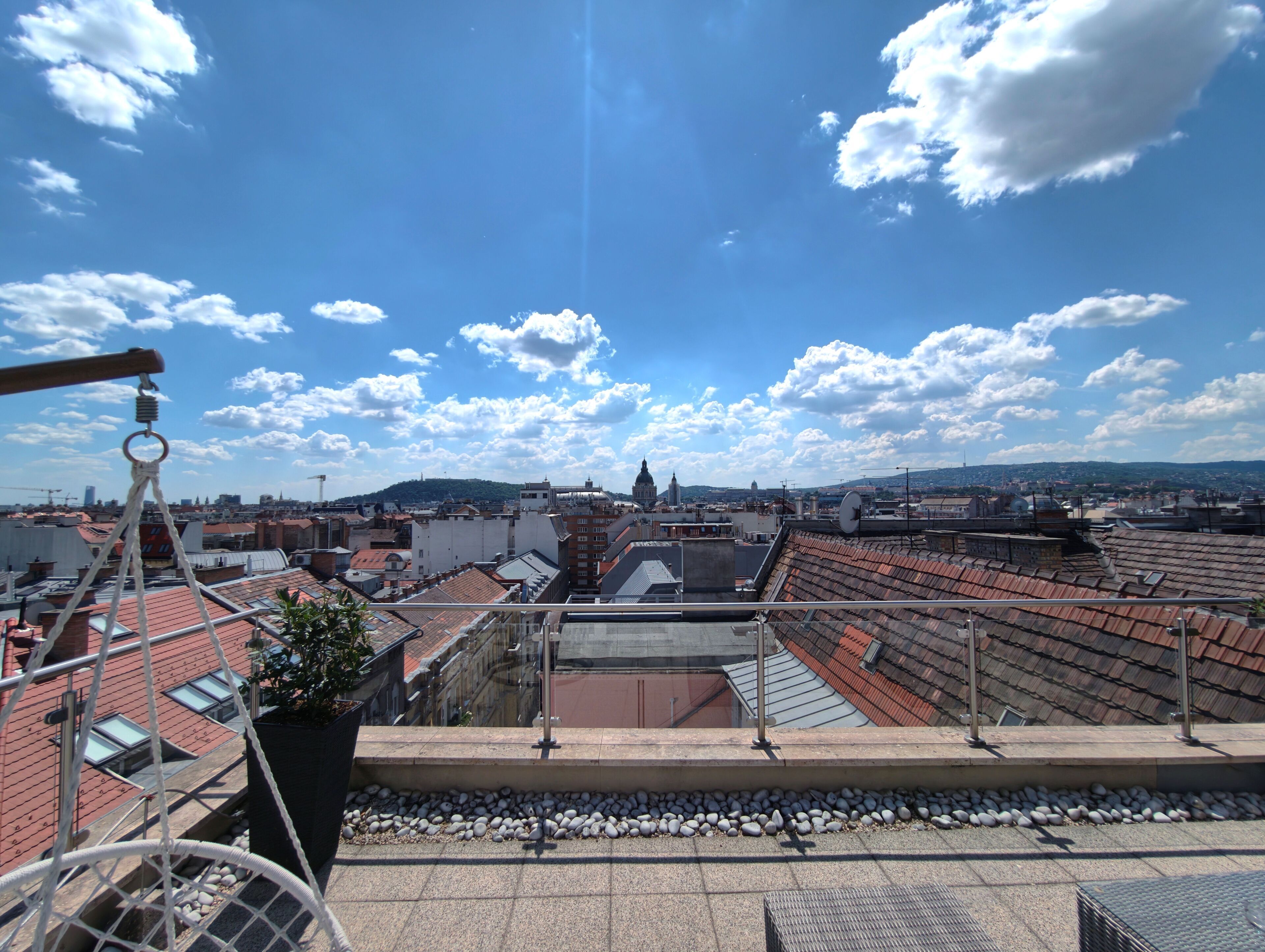 Una terraza en la azotea con vistas al paisaje urbano, incluyendo edificios y una colina distante.