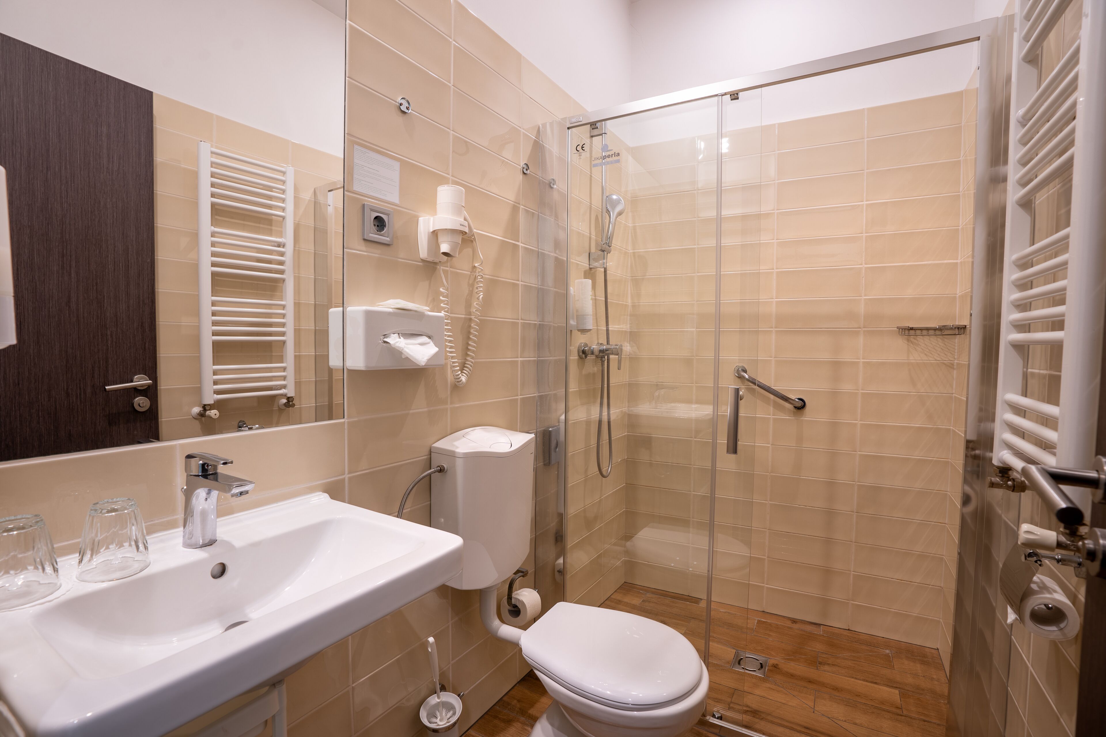 A modern bathroom with a glass-enclosed shower, a white sink with a mirror, and a toilet.