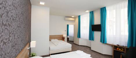 A hotel room with a bed, a desk, a chair, and a TV.
