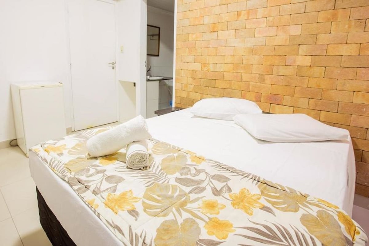Une chambre d’hôtel avec un lit, une porte blanche et un mur en briques.