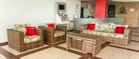 Un vestíbulo con muebles de mimbre, mostrador de recepción y suelo de baldosas.
