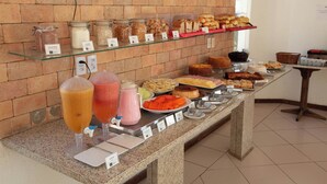 A buffet with various food items and drinks, including jars of spreads and a selection of breads and pastries. - Rede Andrade Ondina Hotel (Salvador)