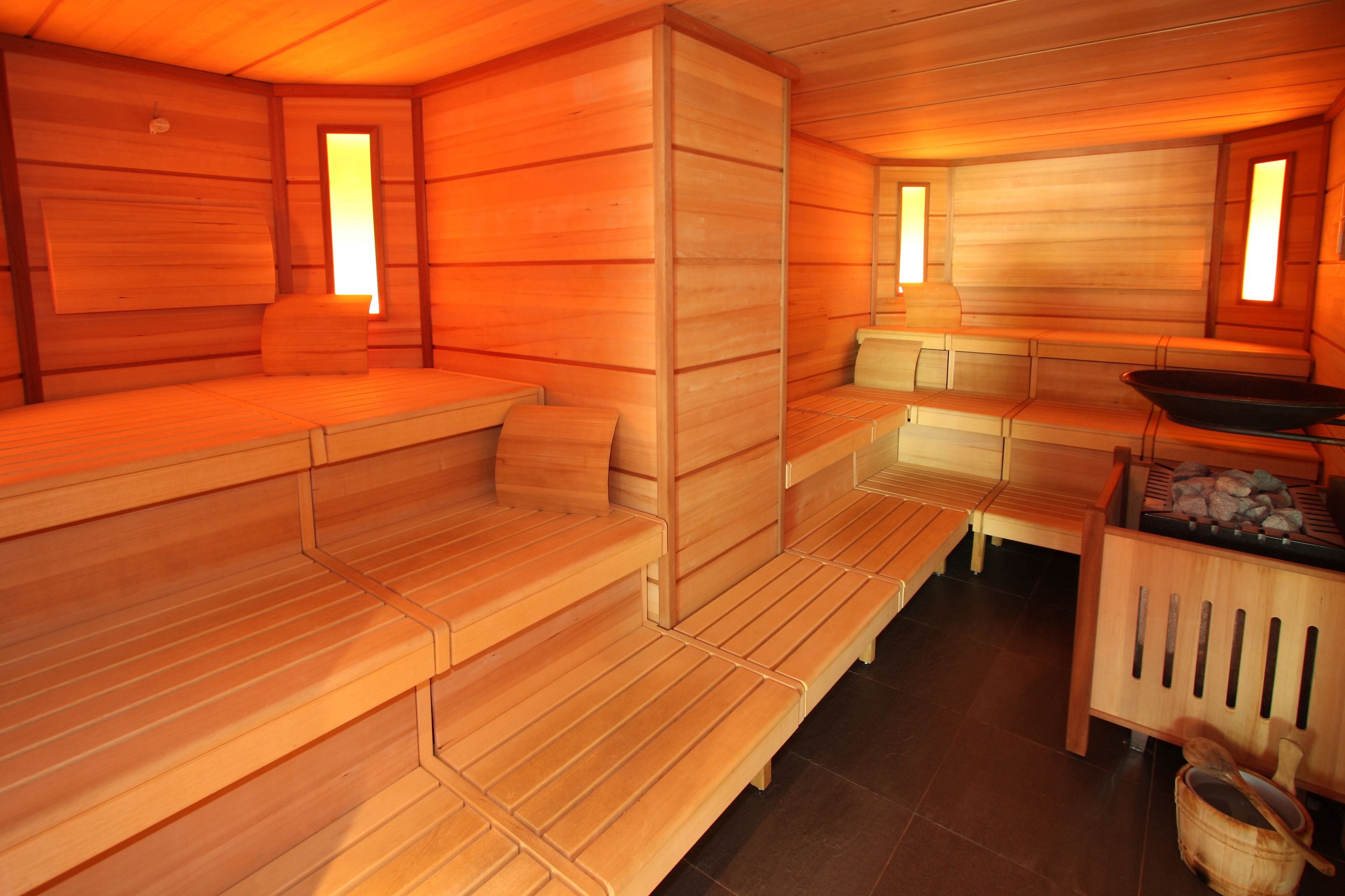 Eine Sauna mit Holzbänken und einem Steingrundschale.