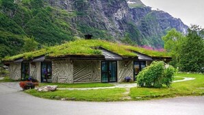 Una casa con techo de hierba, ubicada en una zona montañosa con vistas del paisaje circundante.
