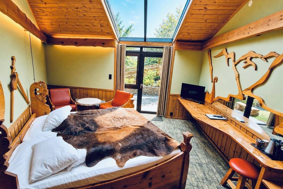 Una habitación con cama, escritorio, televisor y vistas al exterior.