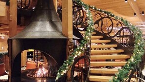 Una escalera de caracol de diseño rústico, una chimenea con leña y un techo de madera.