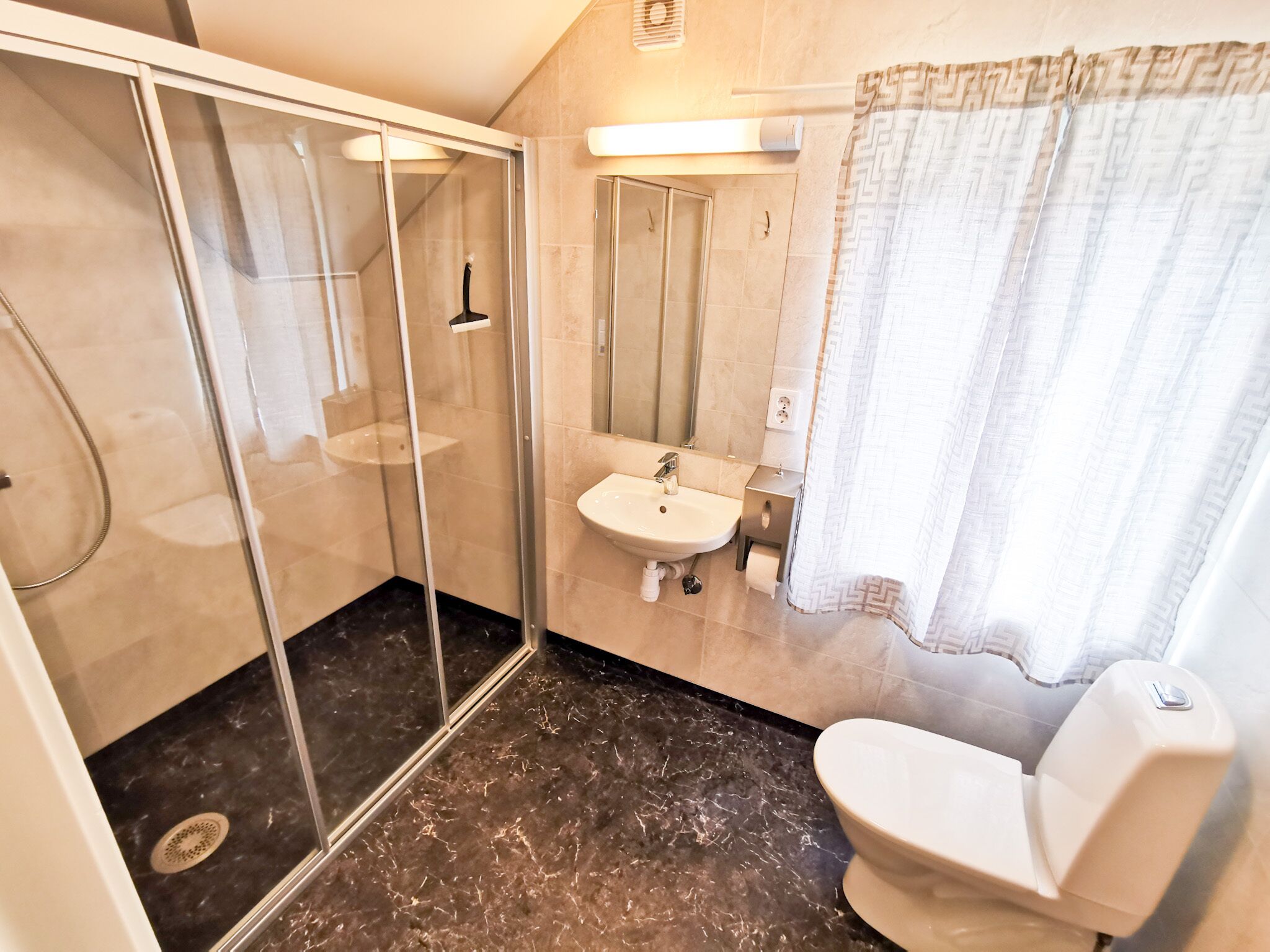 Une salle de bain avec une douche à parois de verre, un lavabo et des toilettes.