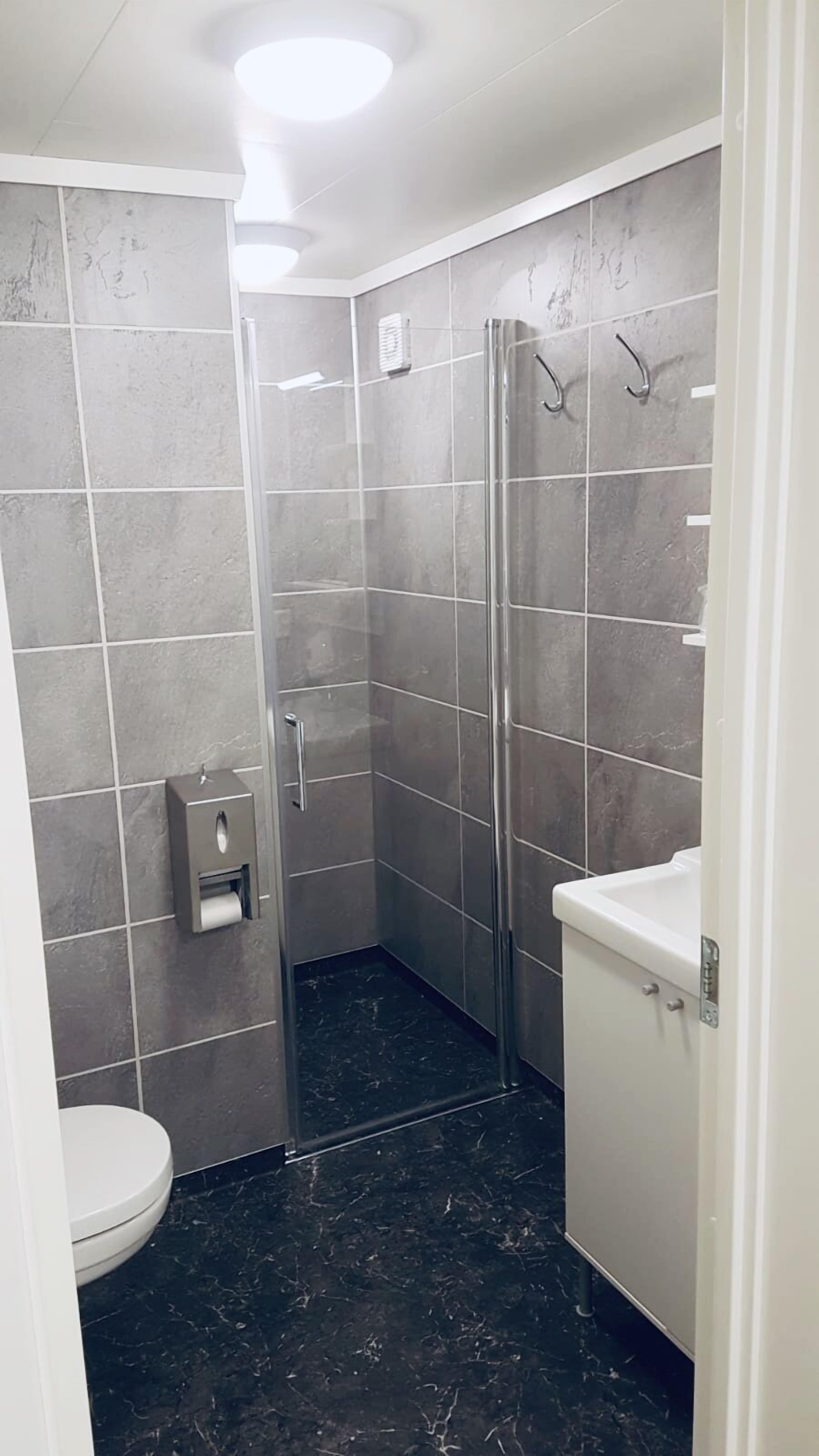 A modern bathroom with a glass-enclosed shower, a toilet, and a sink.