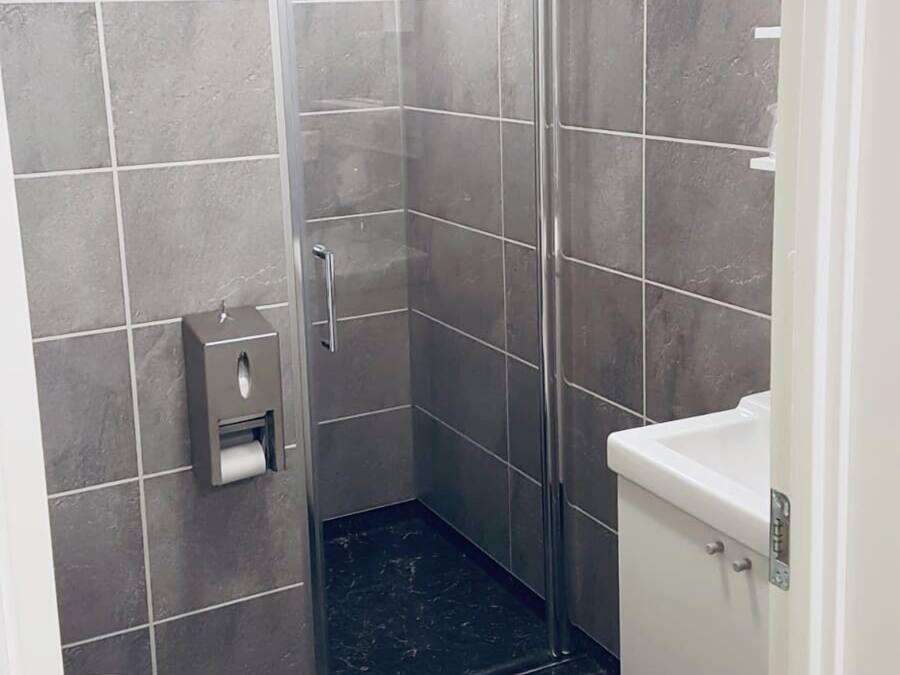 A modern bathroom with a glass-enclosed shower, a toilet, and a sink.