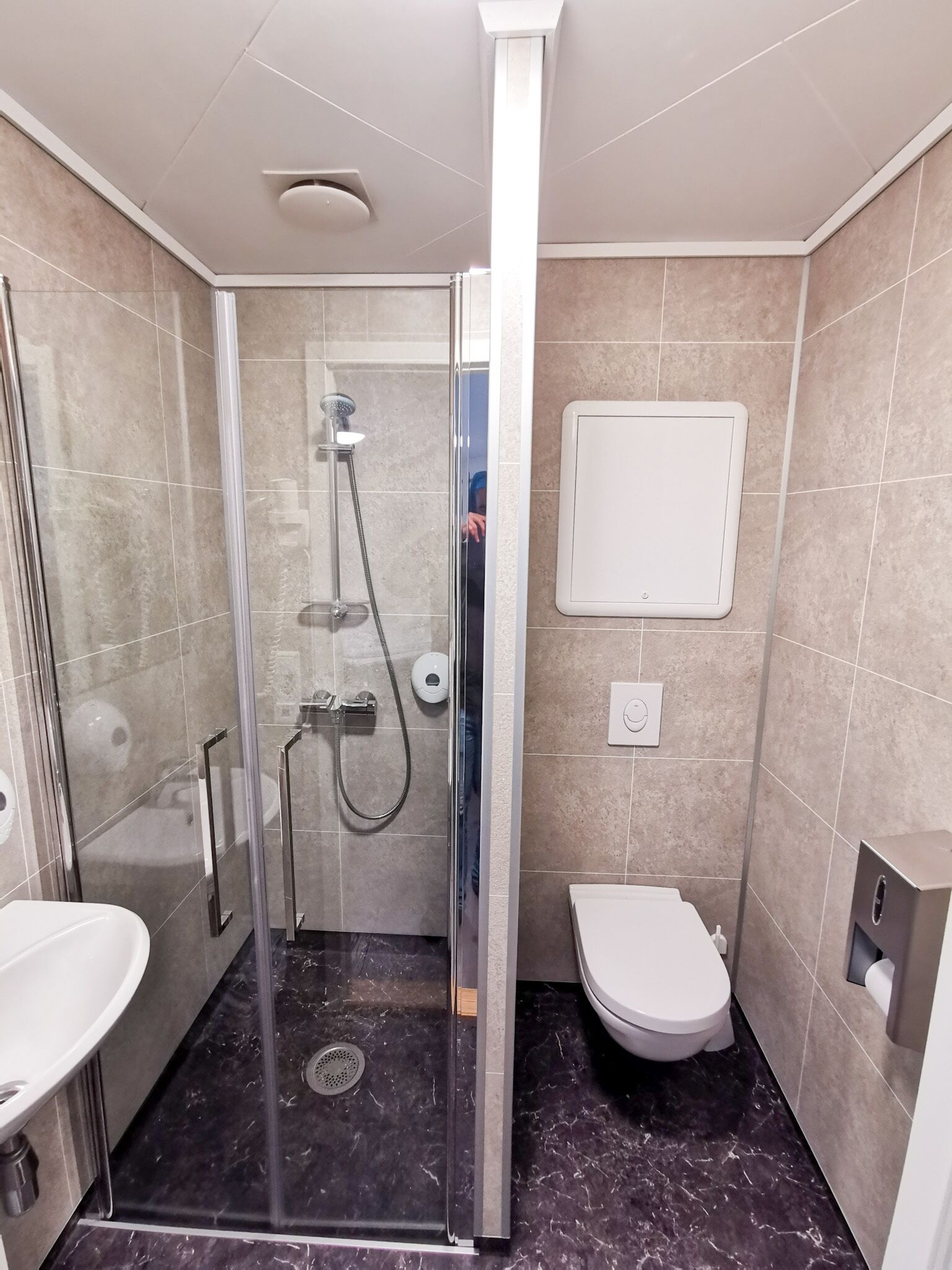 A modern bathroom with a glass-enclosed shower, a toilet, and a sink.
