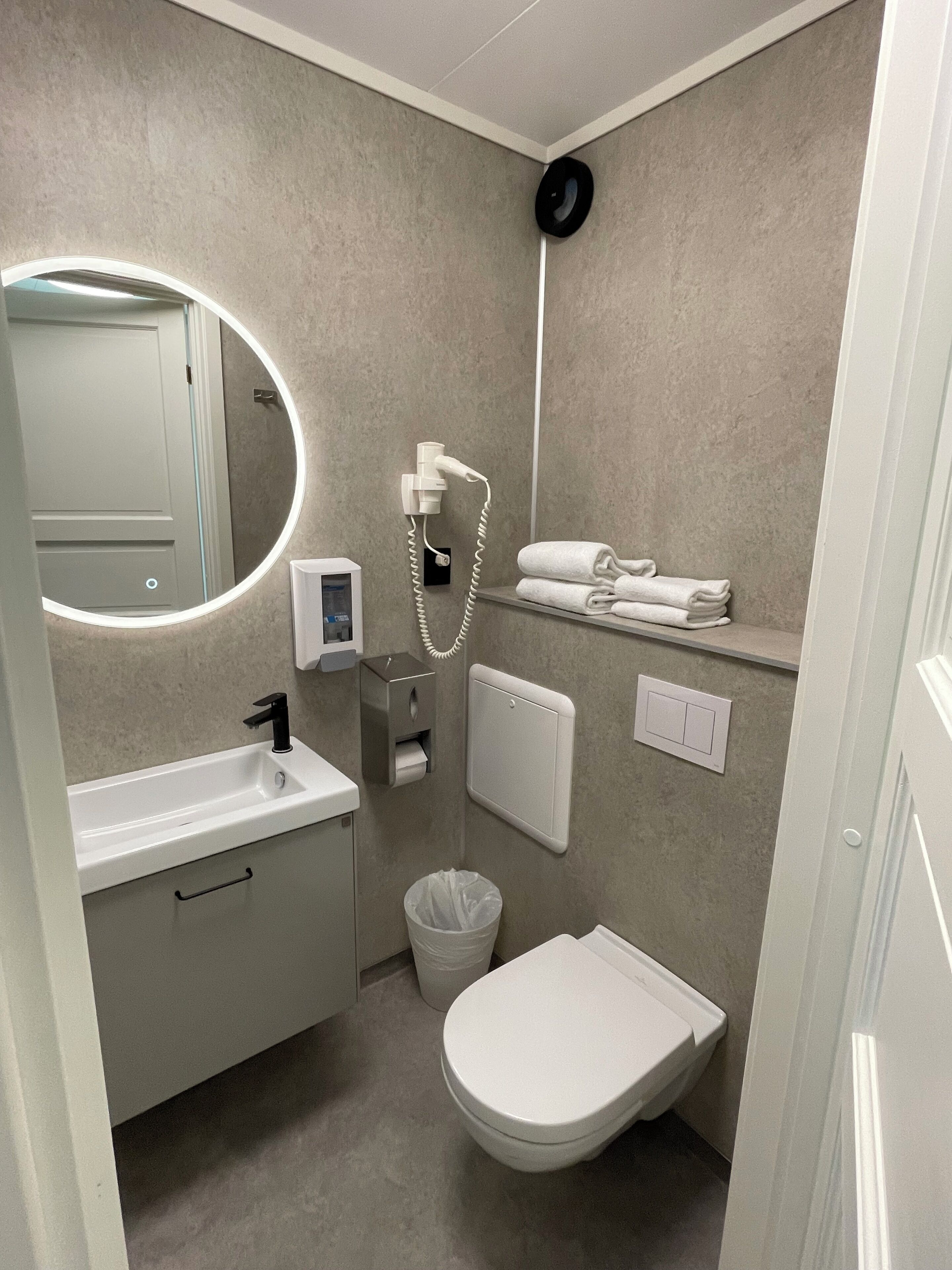 A modern bathroom with a sink, mirror, toilet, and towel rack.