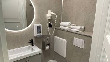A modern bathroom with a sink, mirror, toilet, and towel rack.