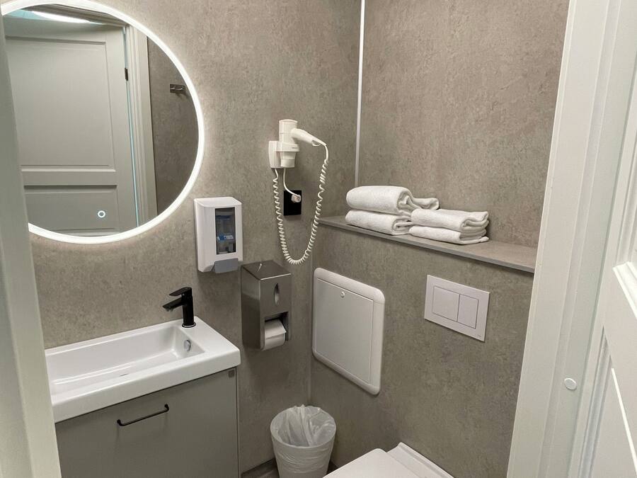 A modern bathroom with a sink, mirror, toilet, and towel rack.