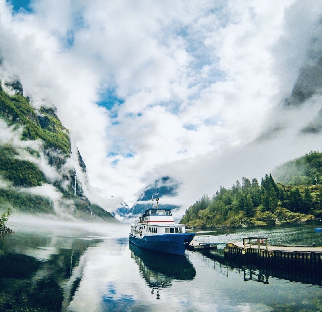 Un barco amarrado en un muelle con montañas al fondo y un cielo despejado.