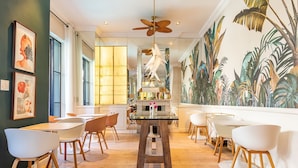A modern dining area with wooden flooring, white chairs, and a central table. - Mountview Guest House (Cape Town)