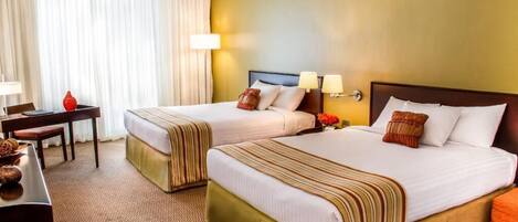 A hotel room with two beds, a desk, and a chair.