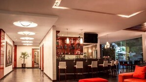 Una hall moderna di un hotel con zona bar, posti a sedere e un'ampia finestra con vista.