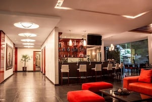 Um lobby de hotel moderno com área de bar, assentos e uma grande janela com vista.