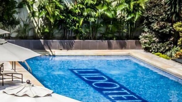 Una piscina con zona relax dotata di tavoli e sedie, immersa nel verde.