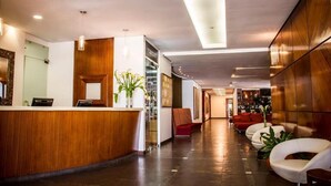Una moderna hall dell'hotel con reception, area salotto e bar.