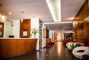 Um hall de hotel moderno com balcão de recepção, área de estar e bar.
