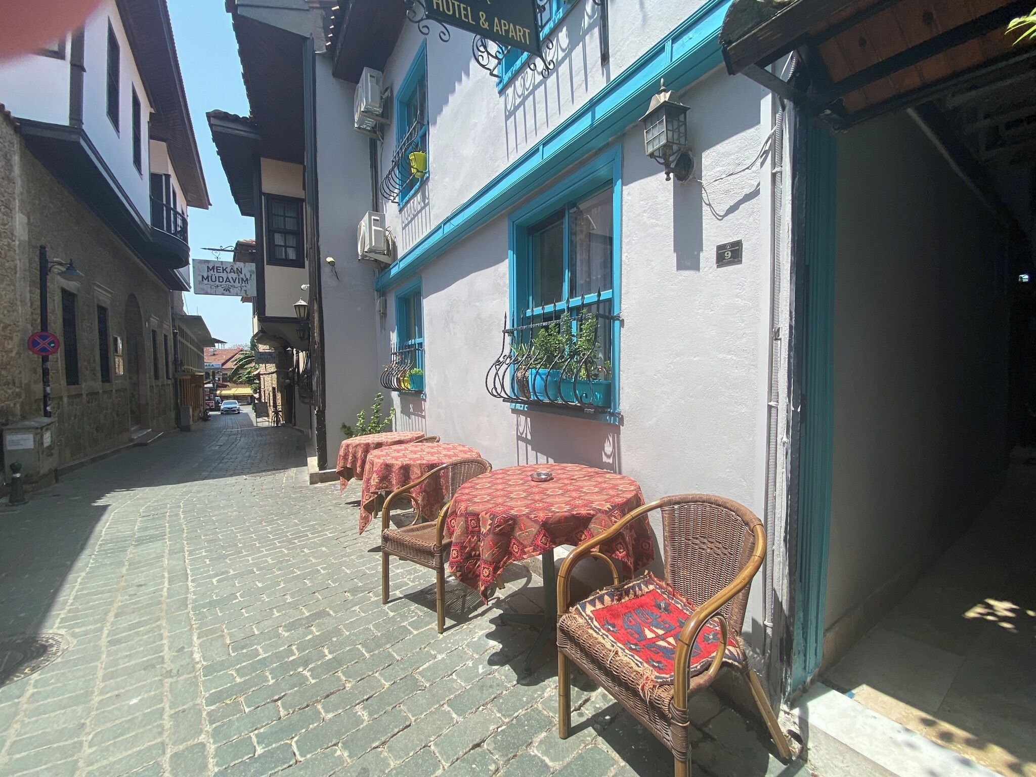 Una estrecha calle adoquinada con un edificio que tiene un marco azul en una ventana y un letrero que dice 