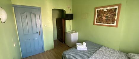 Une pièce comprenant un lit, une chaise, un bureau, une armoire et un tableau accroché au mur.