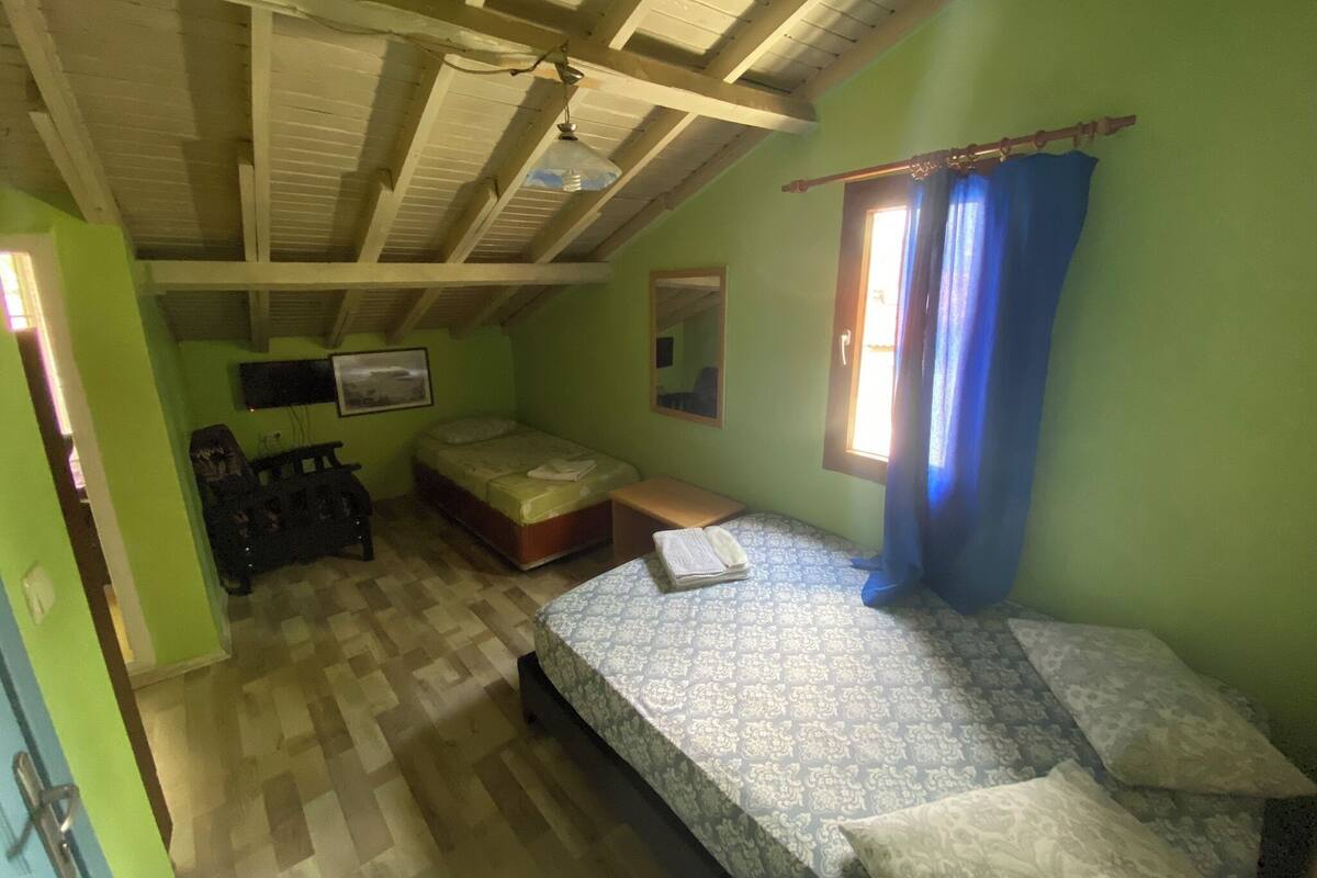 Ein kleiner, gemütlicher Raum mit schrägen Wänden, einem Bett, einem Schreibtisch und einem Stuhl.