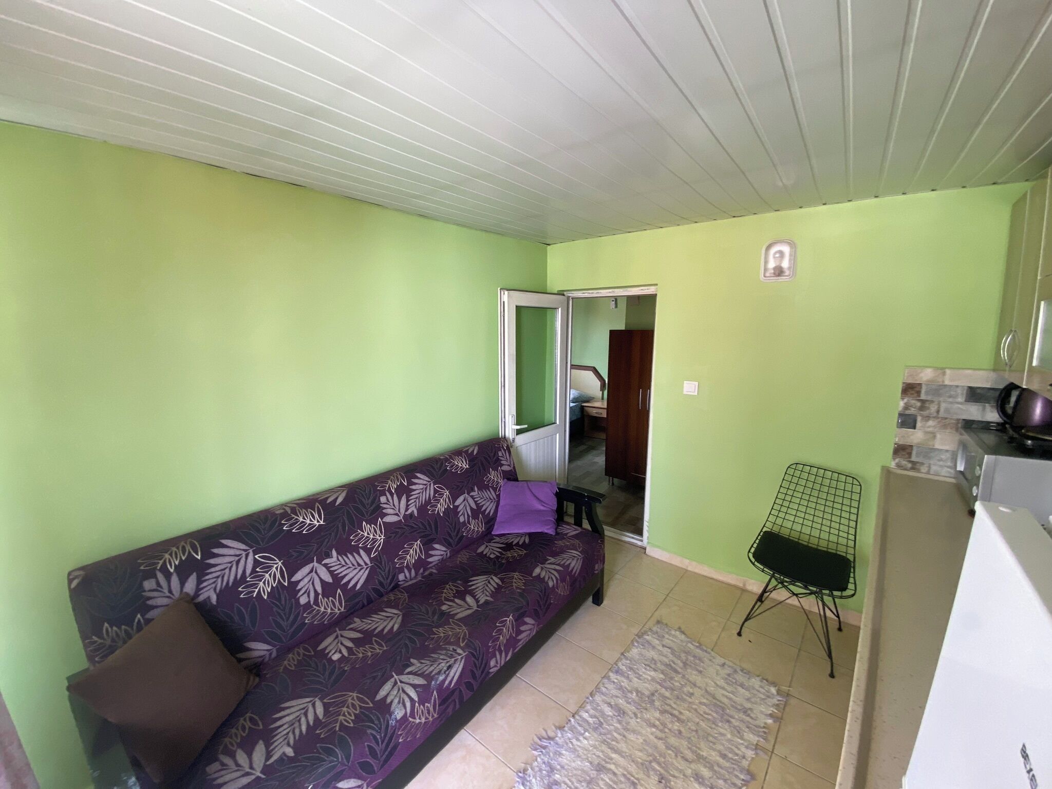 A living room with a sofa, a small table, and a kitchen area with a stove.