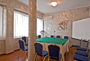 A conference room with a green table, blue chairs, a whiteboard, and a microphone. - Sam Hotel (Monfalcone)