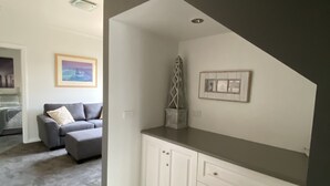 Un interior moderno con una pared de acento gris, muebles de cocina blancos y un sofá gris en la sala.