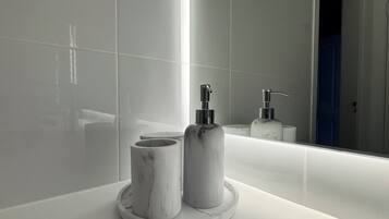 A modern bathroom with a white vanity, a large mirror, and a round sink.