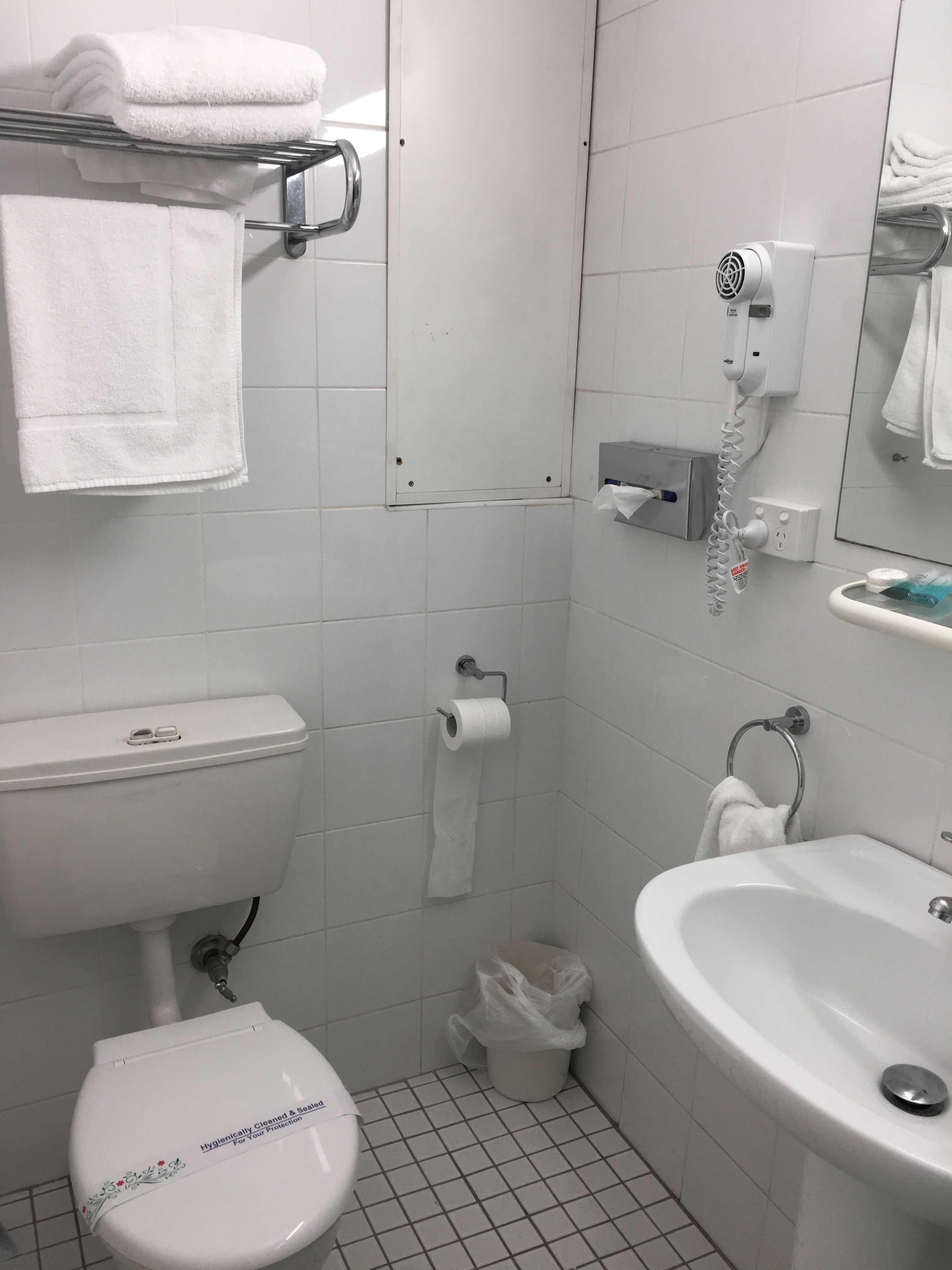 Un baño con inodoro, lavamanos y perchero para toallas.