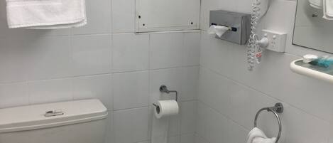 Un baño con inodoro, lavamanos y perchero para toallas.