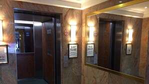 An elevator with a 'Quiet Please' sign, a 'No Smoking' sign, and a 'No Elevator' sign.