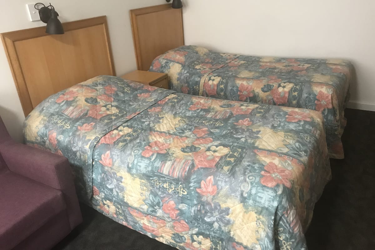 Una habitación con dos camas, cada una con ropa de cama floral, un cabecero de madera y una mesita de noche de madera.