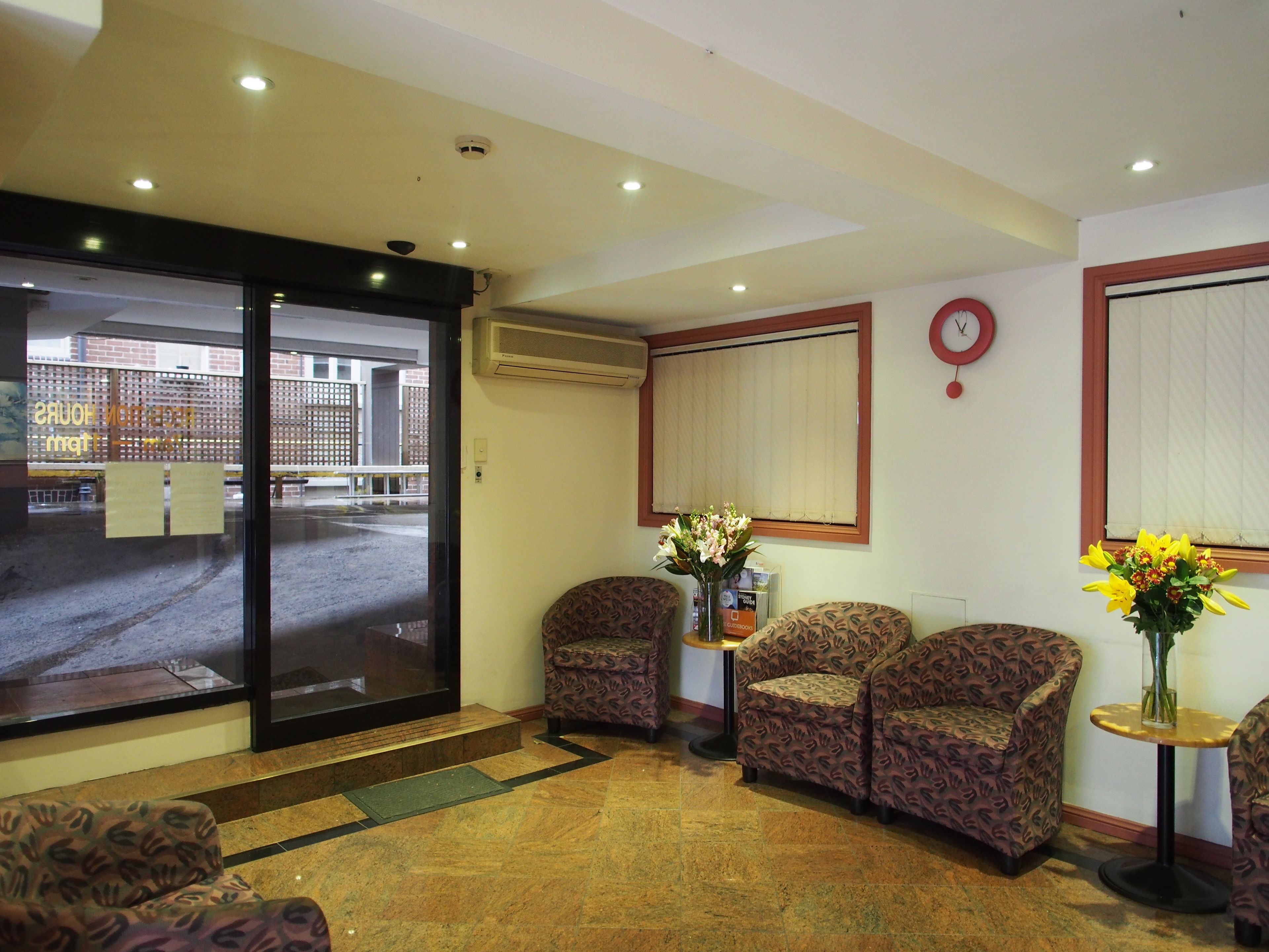 A lobby with patterned chairs, a reception desk, and a large window overlooking a parking area.